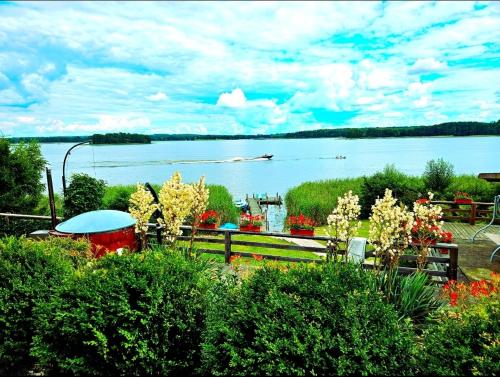 a view of a lake with a table and flowers at Perła Jezioraka Siemiany - Całoroczny 100m Apartament z linią brzegową, banią z jacuzzi i pomostem in Siemiany