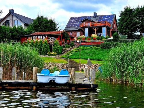a boat on a dock in front of a house at Perła Jezioraka Siemiany - Całoroczny 100m Apartament z linią brzegową, banią z jacuzzi i pomostem in Siemiany