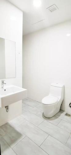 a white bathroom with a toilet and a sink at Sunrise @ Gurney in George Town