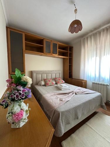 a bedroom with a bed and a table with flowers on it at Avenida House - Regina Hotel Group in Viana do Castelo