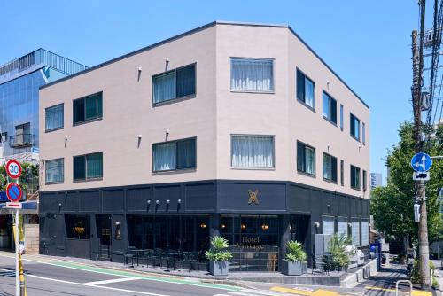 a large white building with black trim on a city street at Hotel Vintage Tokyo Meguro Fudomae in Tokyo