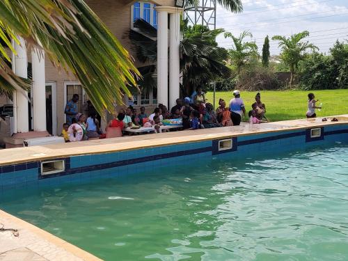 a group of people sitting around a swimming pool at Aloha Hotel & Resort in Oshogbo