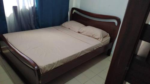 a bed with a wooden frame and white sheets at TUCACAS Punta Brava in Tucacas
