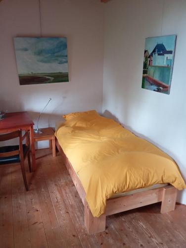 a bed in a room with a desk and a bedspread at Boerderij De Diek'n in Zeerijp