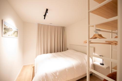 a bedroom with a white bed and wooden shelves at Villa Mariella in Nieuwpoort