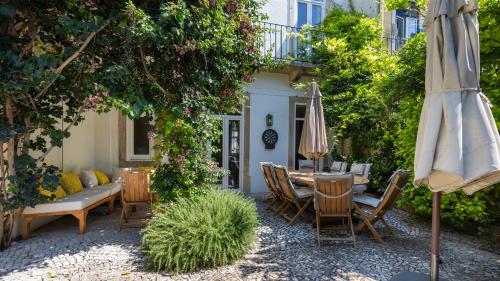 eine Terrasse mit Tisch und Stühlen und einem Sonnenschirm in der Unterkunft Garden Mansion in Historic Center by LovelyStay in Lissabon