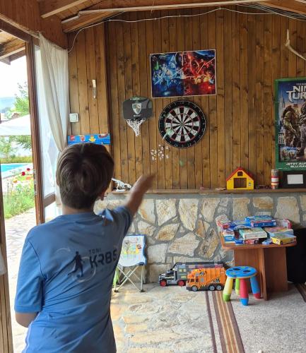 a boy is pointing at a dart board on a wall at Hotel Zenit Satovcha in Satovcha
