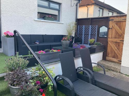 a patio with chairs and potted plants and a wooden door at North Coast Retreat in Portstewart