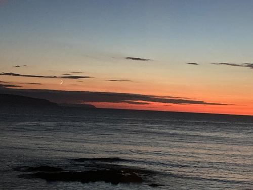 a sunset over the ocean with a rock in the water at North Coast Retreat in Portstewart