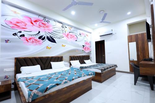 a bedroom with two beds and pink flowers on the wall at Shri Girraj Residency in Mathura