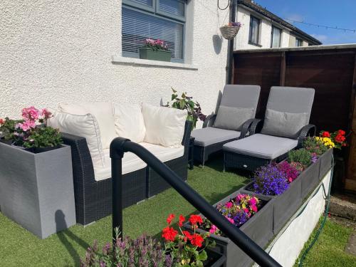 a patio with two chairs and flowers in a yard at North Coast Retreat in Portstewart