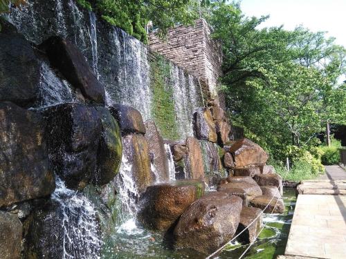 einem Wasserfall vor einer Steinmauer in der Unterkunft furorai KANAMATI Floral Kanamachi - Vacation STAY 12218 in Tokio