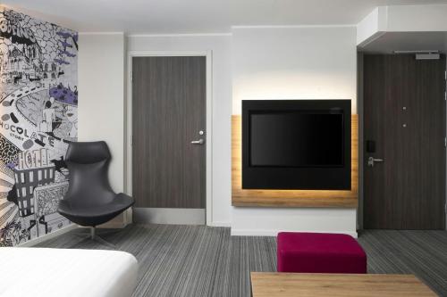 a room with a tv and a chair and a couch at Moxy York in York