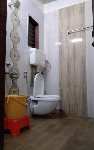 a bathroom with a toilet and a bucket in it at Om Datta Krupa Niwas Cottage in Mahabaleshwar