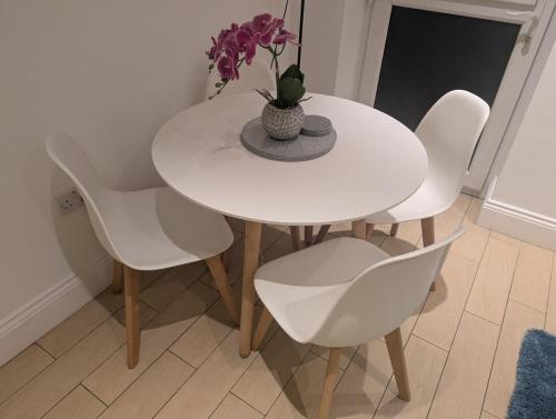 una mesa blanca con sillas blancas y un jarrón con flores en City Escape – 1 Bedroom Flat in Swansea Centre, en Swansea