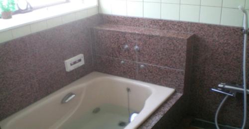 a bathroom with a tub and a brown tiled wall at Kakinoen / Vacation STAY 3939 in Nakagawa