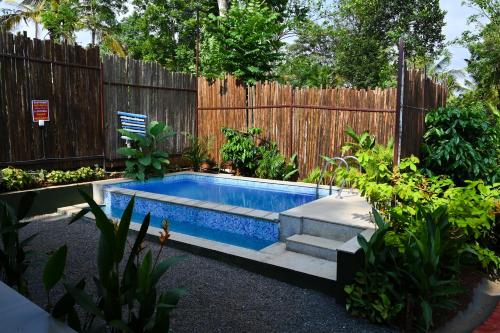 a swimming pool in a backyard with a wooden fence at Mcafe Private Pool Plantations by Greenescapes in Kenichira