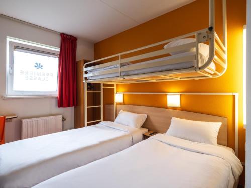 two beds in a room with a bunk bed at Premiere Classe Hotel Breda in Breda
