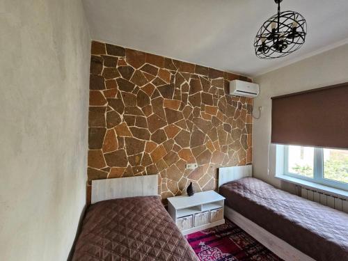 a bedroom with two beds and a stone wall at Loft Comfort House in Yerevan in Yerevan