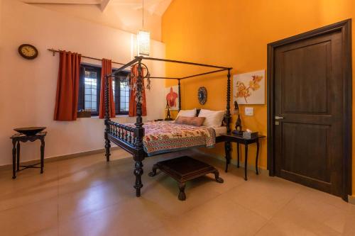a bedroom with a canopy bed and a door at StayVista at Wings On Water - Riverview Villa with Pool in Anjuna