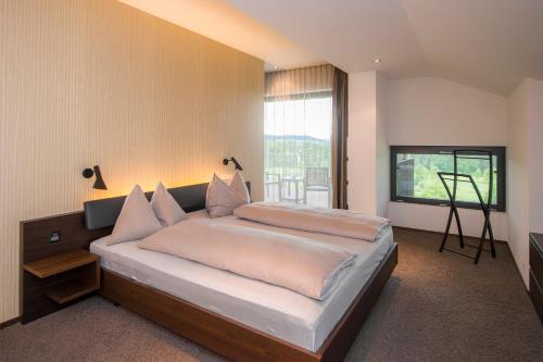 a bedroom with a large bed and a large window at Wellnesshotel Golfpanorama in Lipperswil