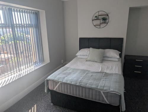 a bedroom with a bed with a window and a mirror at Comfortable 3 Bedroom House with Easy City Access in Swansea