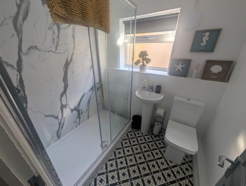 a bathroom with a shower and a toilet and a sink at Comfortable 3 Bedroom House with Easy City Access in Swansea