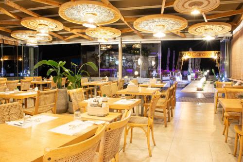 a restaurant with wooden tables and chairs and chandeliers at Yianna Caravel Suites "by Checkin" adults only in Amoudara Herakliou