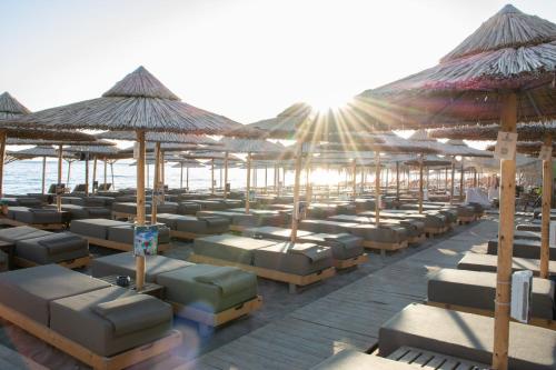 a row of beds on the beach with umbrellas at Yianna Caravel Suites "by Checkin" adults only in Amoudara Herakliou