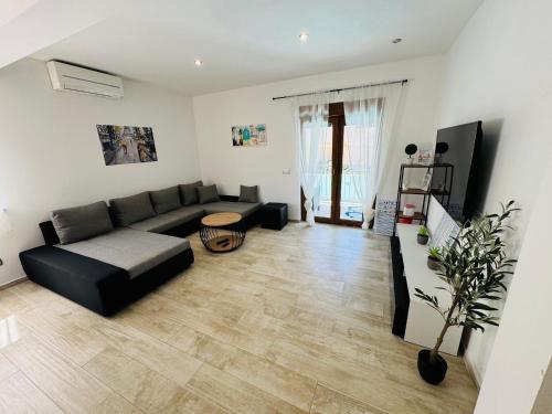 a living room with a black couch and a wooden floor at Kuca za odmor Romina in Umag