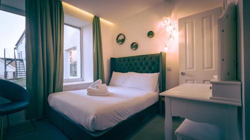 a bedroom with a bed with a desk and a window at The Feather's Hotel Newquay in Newquay