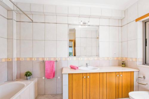 a bathroom with a sink and a tub and a mirror at Villa Ribeiro Tomas by Villa Plus in Loulé