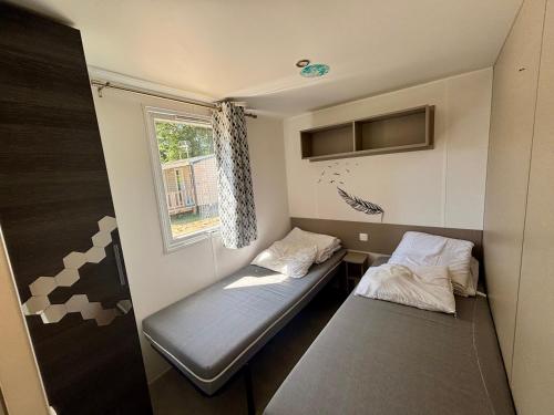 a small room with two beds and a window at Mobil-home 4-6 personnes proche zoo de beauval in Veuzain-sur-Loire