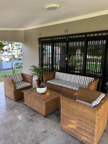 a patio with wicker couches and a coffee table at 47 Gem Holiday House in Lilongwe