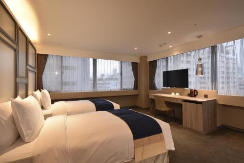 a hotel room with a bed, desk and television at Green World ZhongXiao in Taipei