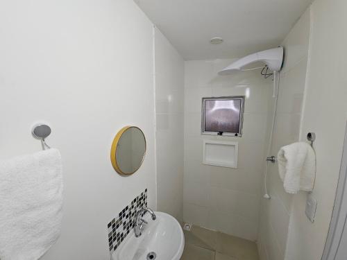 a white bathroom with a sink and a mirror at Loft Nicolau Garcia in São José