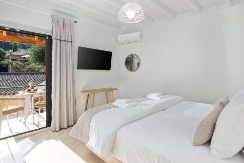 a white bedroom with a bed and a balcony at Bella Vista Beach Hotel in Benitses
