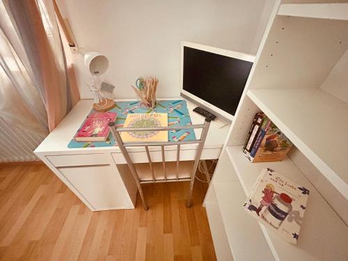 a small white desk with a computer monitor and books at Lunas FeWo in Römerberg