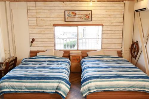 two beds in a room with a window at HB2B 小田原 港徒歩3分 ハワイアン 4名可能 箱根板橋駅徒歩8分 早川駅徒歩7分8 minutes by car from Odawara Station 3 mins walk to port Hawaiian in Odawara