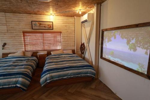 two beds in a room with a large window at HB2B 小田原 港徒歩3分 ハワイアン 4名可能 箱根板橋駅徒歩8分 早川駅徒歩7分8 minutes by car from Odawara Station 3 mins walk to port Hawaiian in Odawara