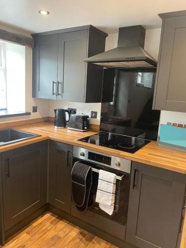 a kitchen with gray cabinets and a stove top oven at 2 bedroom country cottage in the Lake District in Penrith
