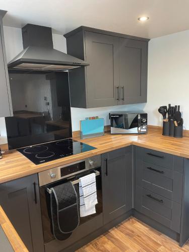 a kitchen with gray cabinets and a stove top oven at 2 bedroom country cottage in the Lake District in Penrith