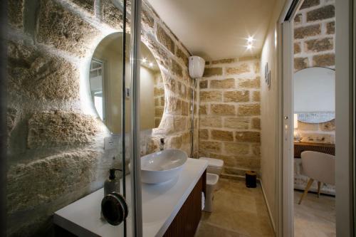 Baño con paredes de piedra, lavabo y espejo en La Dimora del Sale - Ville con piscina, en Favignana
