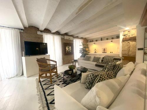ein Wohnzimmer mit einem weißen Sofa und einem Fernseher in der Unterkunft Valencia Luxury - Boutique El Carmen in Valencia