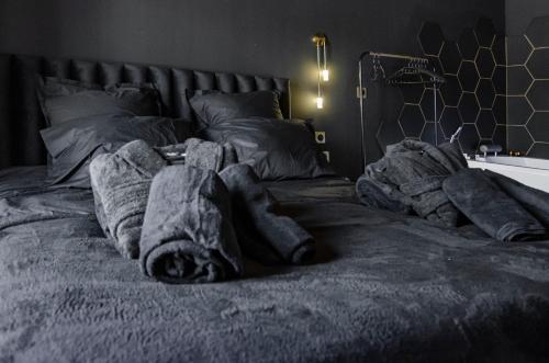 un letto con un mucchio di coperte sopra di Suite Balneo Hammam Noire et Or a Saint-Étienne