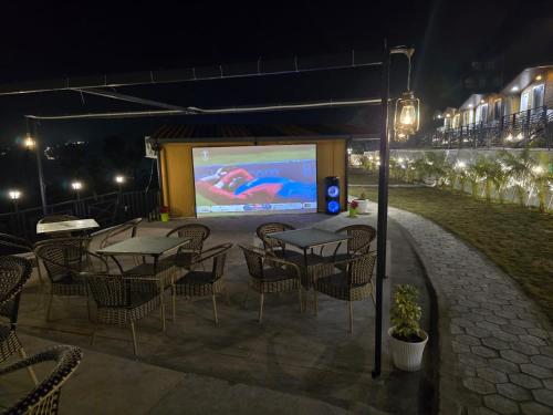 a stage with tables and chairs in front of a screen at Nature on the Rocks Glamping Resort in Shivpuri