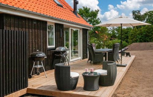 una terraza de madera con parrilla, sillas y sombrilla en Beautiful Home In Gudhjem With Wifi, en Gudhjem
