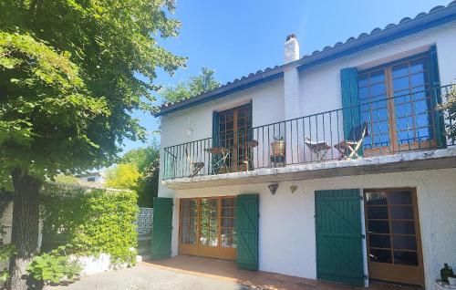 una casa bianca con porte verdi e balcone di Awesome Home In Thézan Les Béziers a Thèzan-lès-Béziers