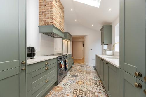 a kitchen with green cabinets and a tile floor at Bob Hannah Cottage in Cockfield