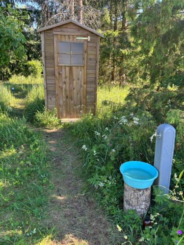 a wooden out house in a field with a bucket at Bubble House glamping telk in Sõmeru